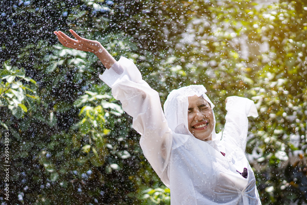 雨天亚洲女人在户外穿着雨衣。她很开心。