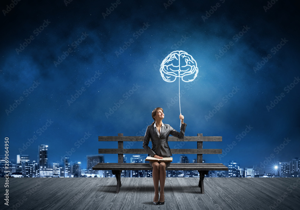 Young woman holding open book on bench