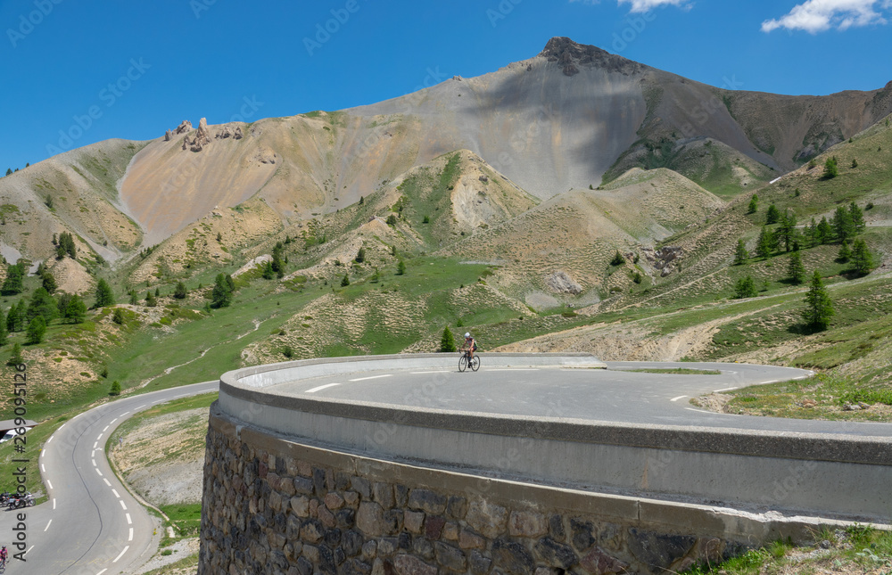 运动员骑着公路自行车沿着阿尔卑斯山风景优美的岔道行驶。