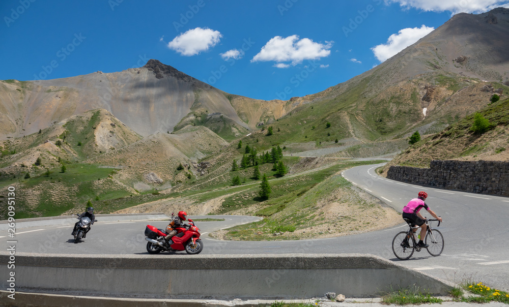 骑摩托车和公路自行车的旅行者在阿尔卑斯山的一条岔道上骑行。