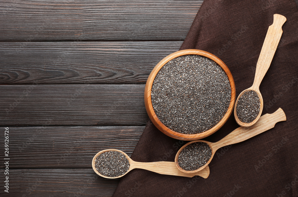 Spoons and bowl with chia seeds on wooden table