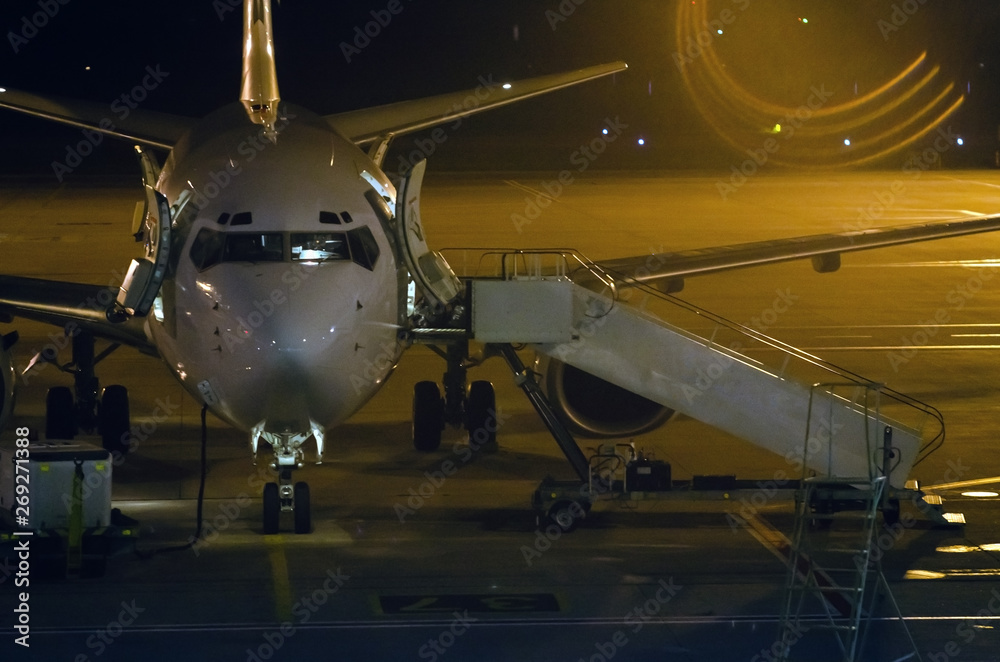 Airplane and passenger steps of the vehicle on the platform of the night airport