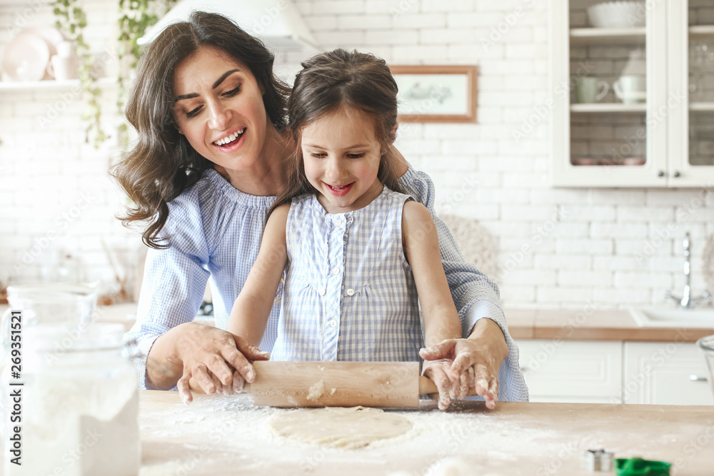 Happy mother with daughter preparing cookies in kitchen at home