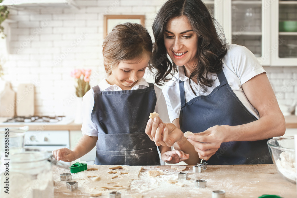 Happy mother with daughter preparing cookies in kitchen at home