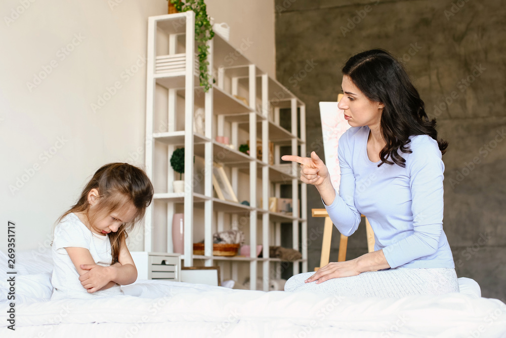 Mother scolding her naughty little daughter at home