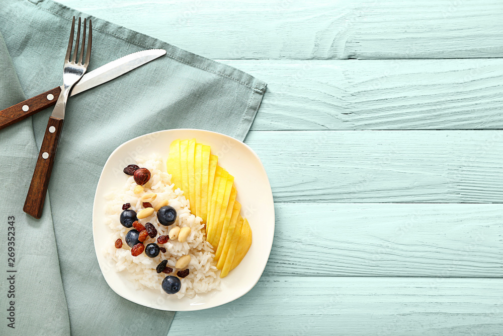 Plate with tasty mango and boiled rice on wooden table