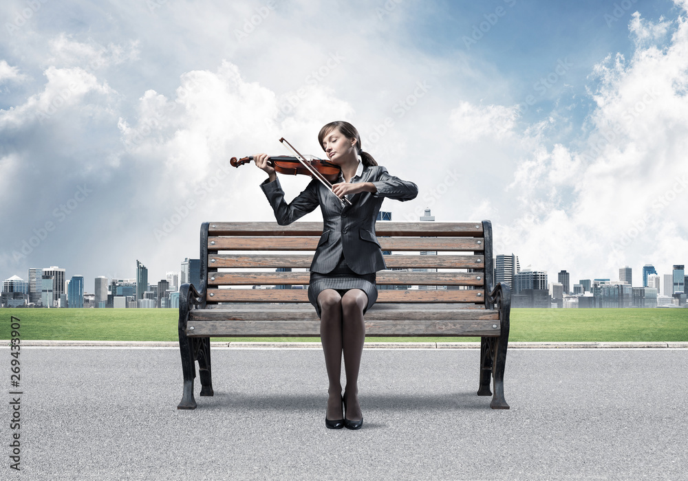 Young woman with violin sitting on wooden bench