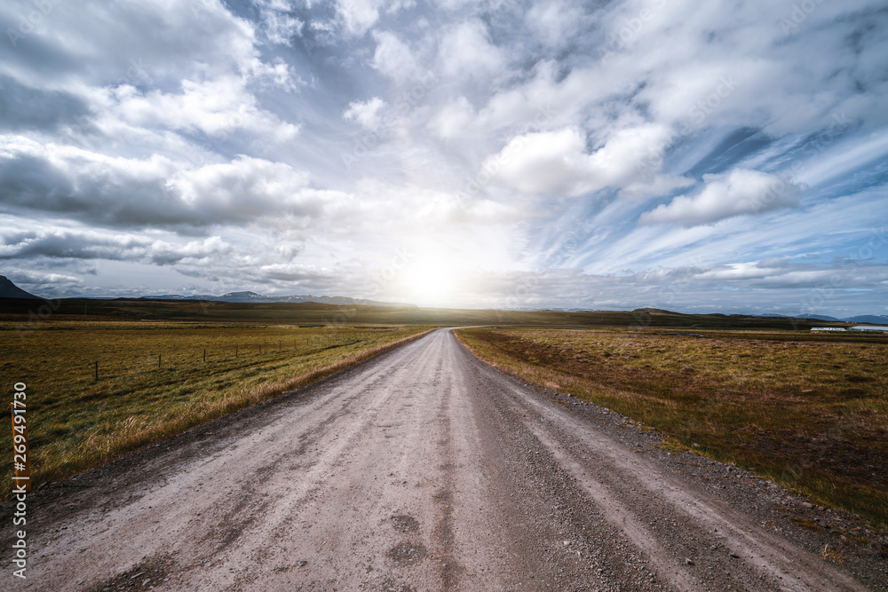 Empty gravel dirt road through countryside landscape and grass field. Nature off road travel trip fo