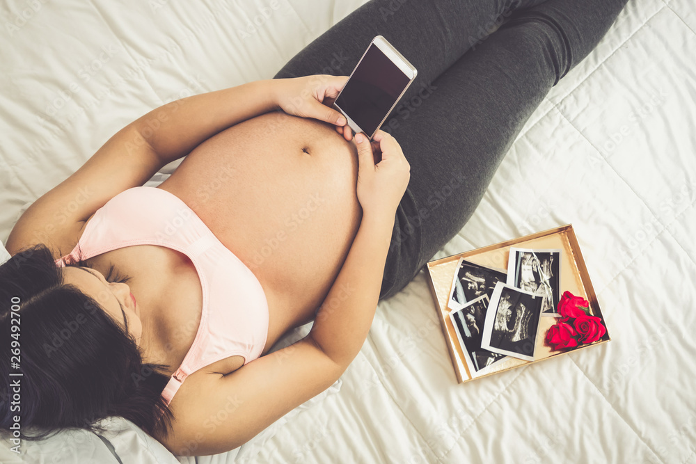 Pregnant woman feeling happy at home while taking care of her child. The young expecting mother hold