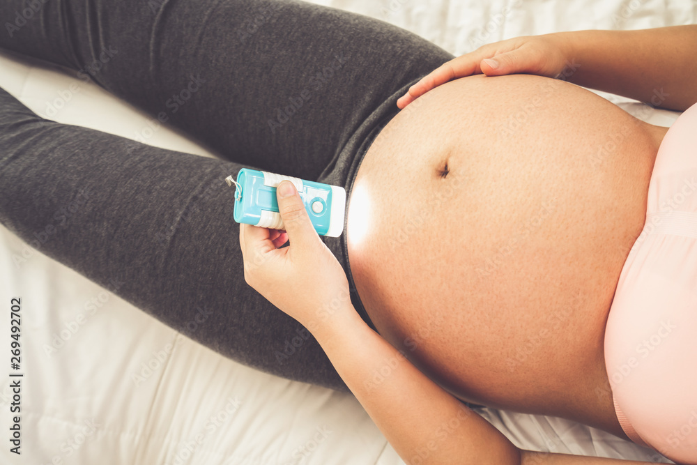 Pregnant woman feeling happy at home while taking care of her child. The young expecting mother hold