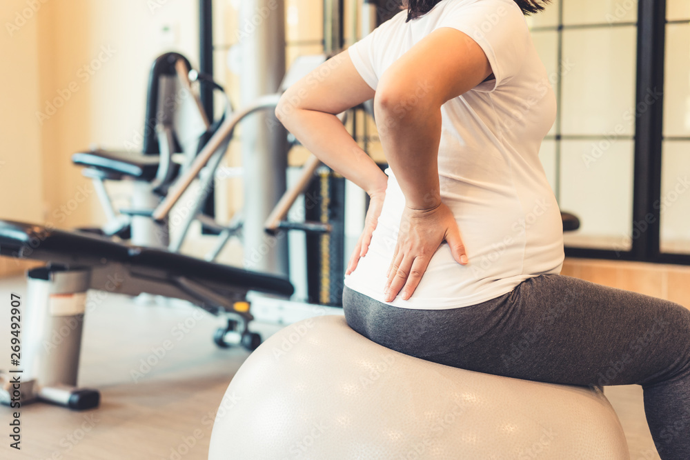 Active pregnant woman exercise in fitness center at yoga room. The young expecting mother holding ba