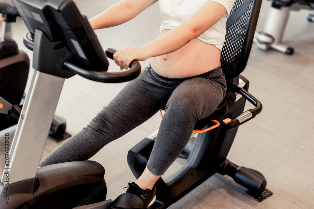 Active pregnant woman exercise in fitness center at yoga room. The young expecting mother holding ba