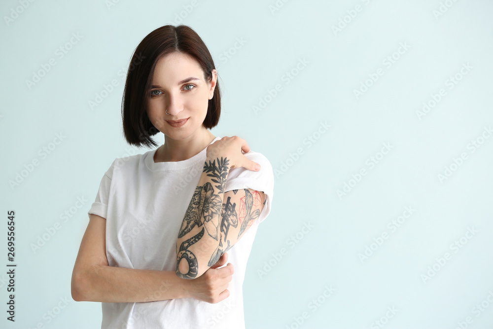 Beautiful tattooed woman on light background