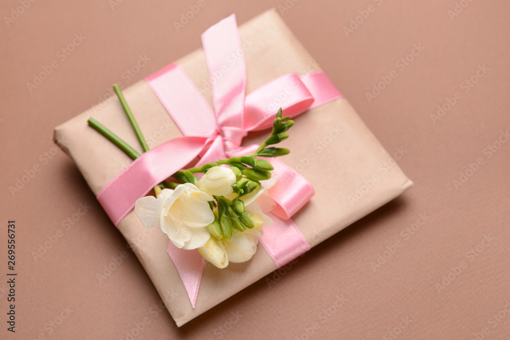 Gift with beautiful freesia flowers on color background