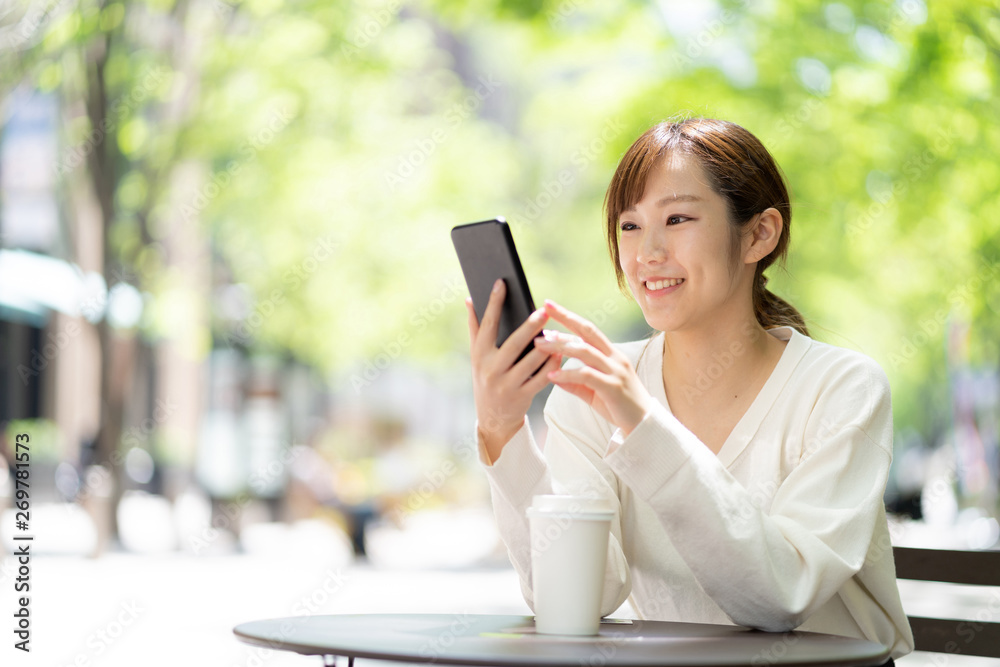 オープンカフェでスマートフォンを使う女性