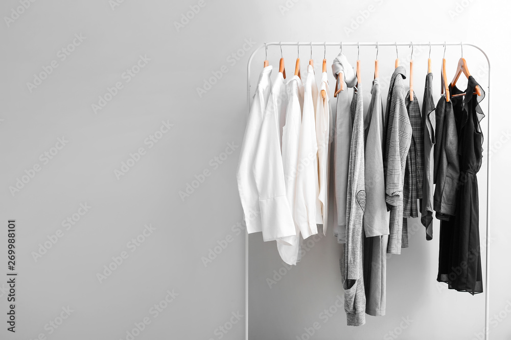 Rack with stylish clothes on light background