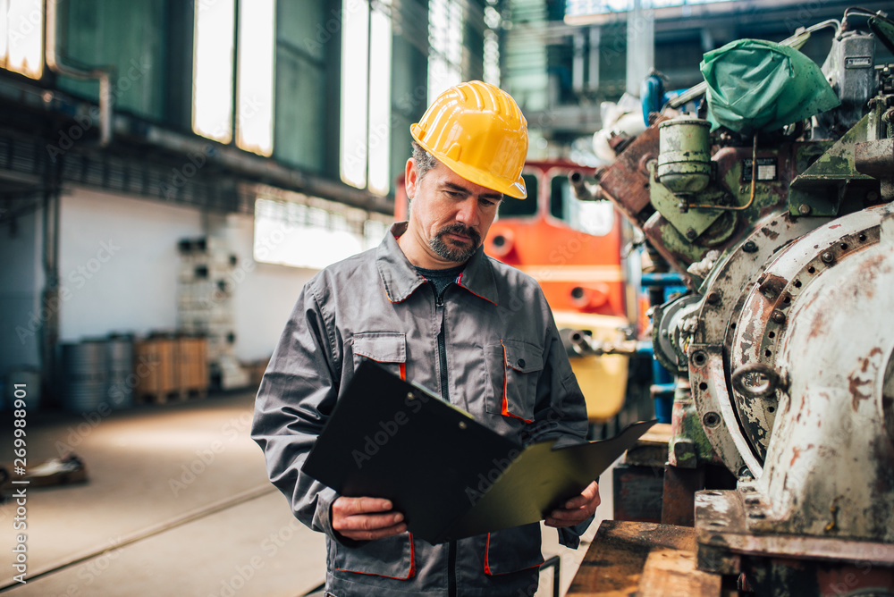 Portrait of a serious factory worker looking at documents.