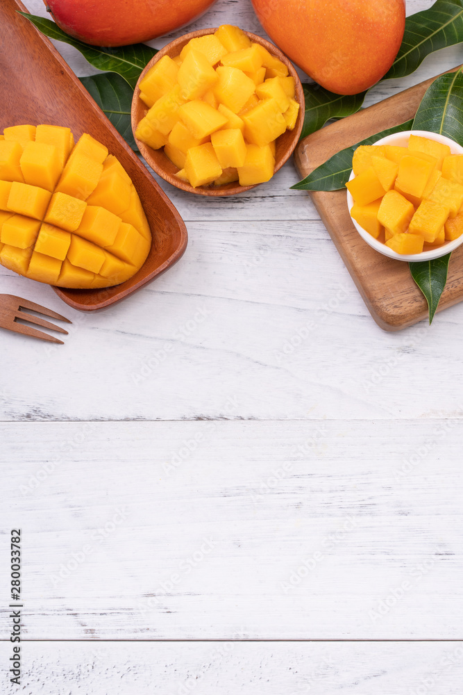 Fresh chopped mango on a tray and bright rustic wooden background. Tropical summer fruit design conc