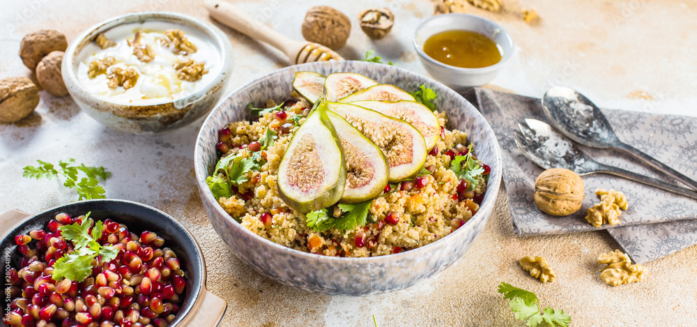 close-up view of tasty healthy couscous salat with figs fruits, nuts and pomegranate seeds 