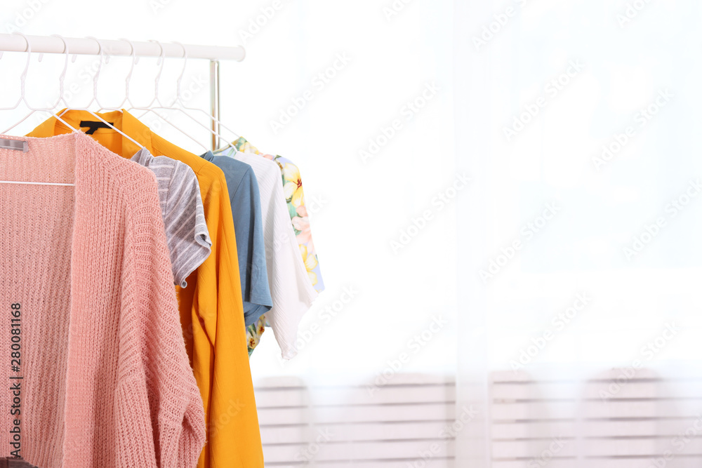 Womens hip clothing store interior concept. Row of different colorful female clothes hanging on rac