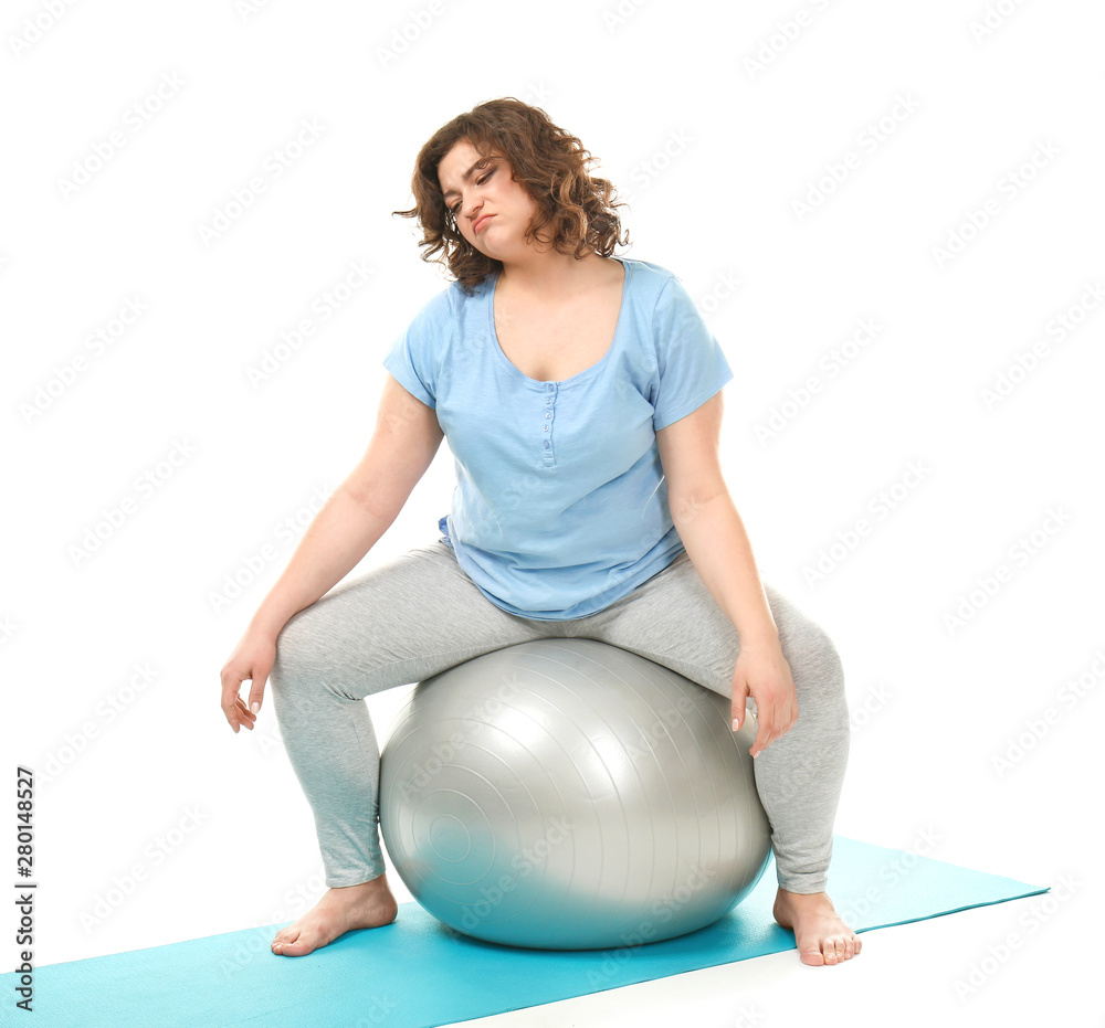 Displeased overweight woman sitting on fitball against white background