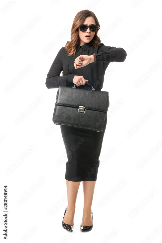 Worried young businesswoman looking at watch on white background