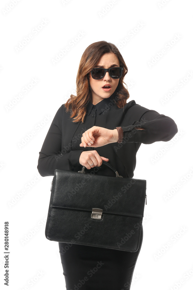 Worried young businesswoman looking at watch on white background