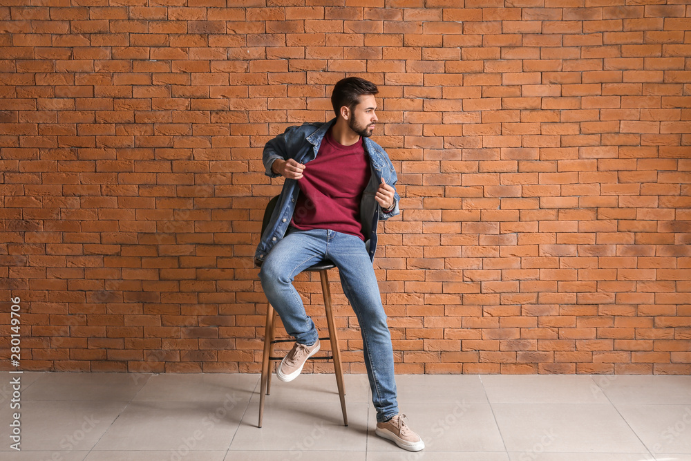 Fashionable young man near brick wall