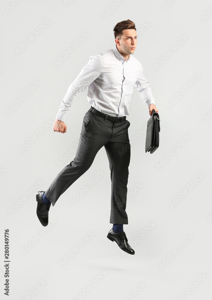 Jumping young businessman on grey background