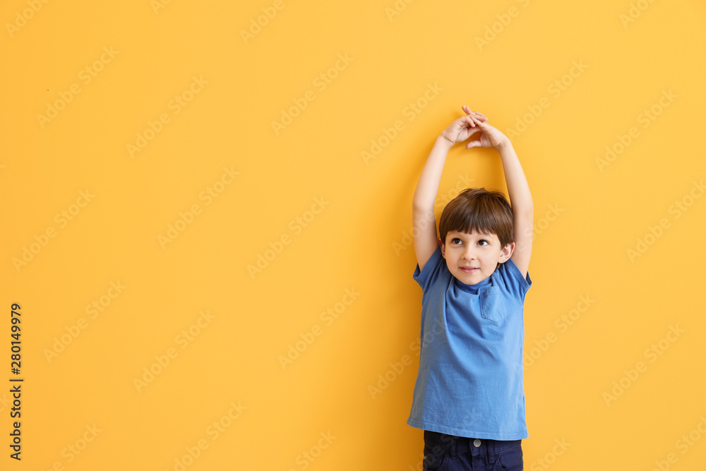 Cute little boy measuring height near color wall