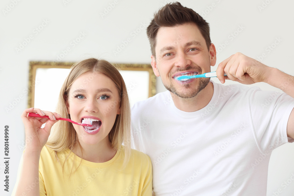 Happy couple cleaning teeth at home