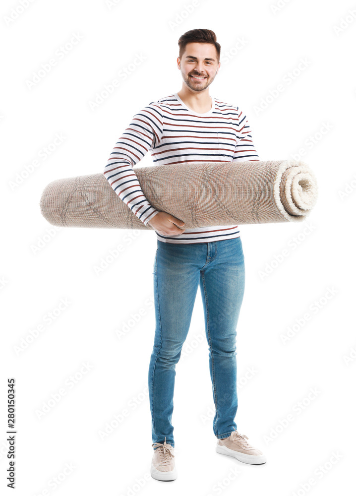 Young man holding rolled carpet against white background