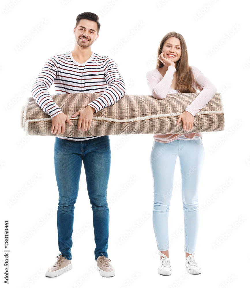 Young couple holding rolled carpet against white background