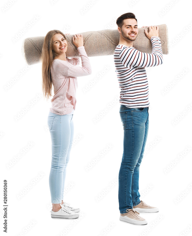 Young couple holding rolled carpet against white background