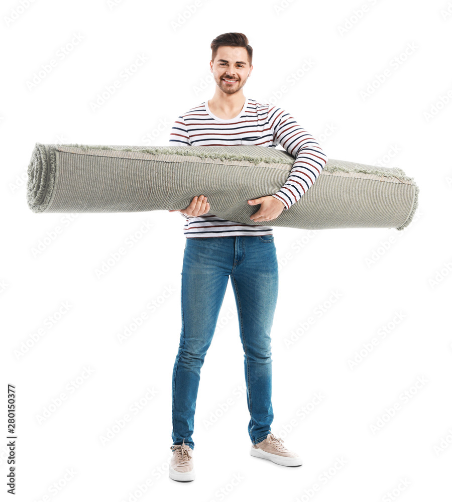 Young man holding rolled carpet against white background