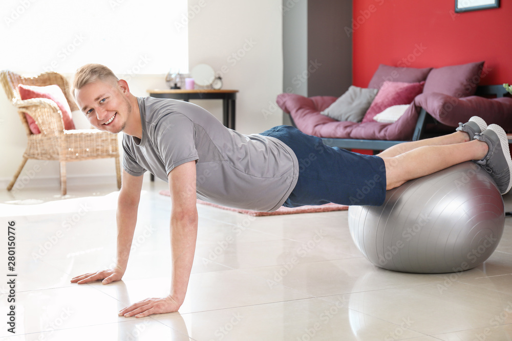 Young man doing exercise with fitball at home