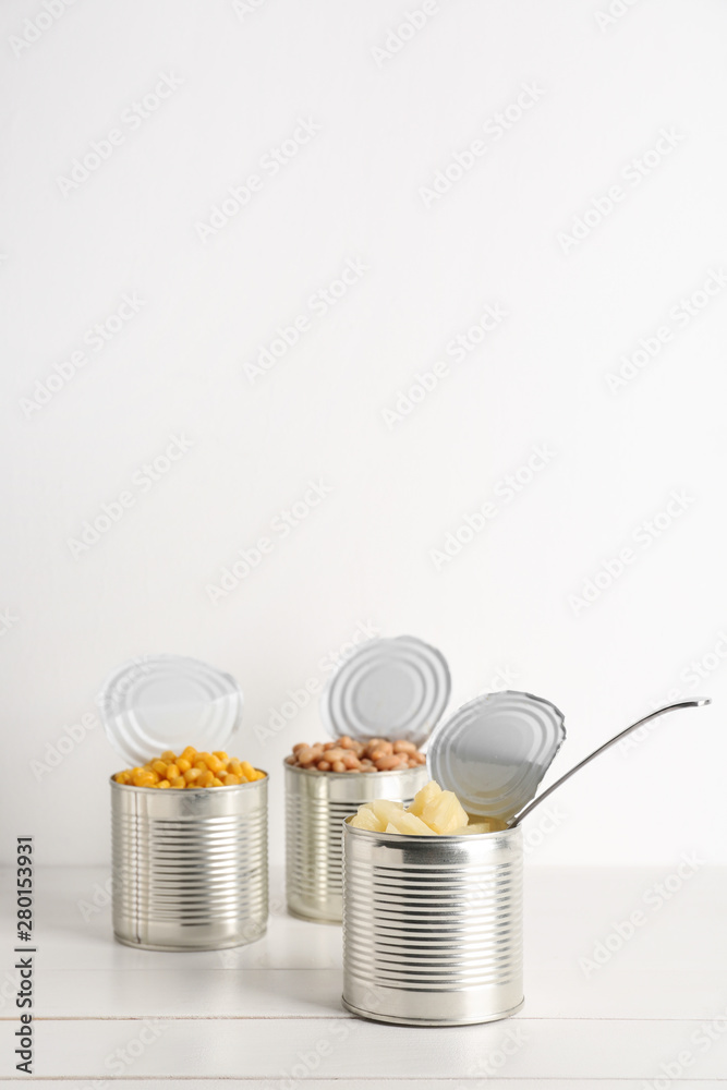 Tin cans with different food on white wooden table