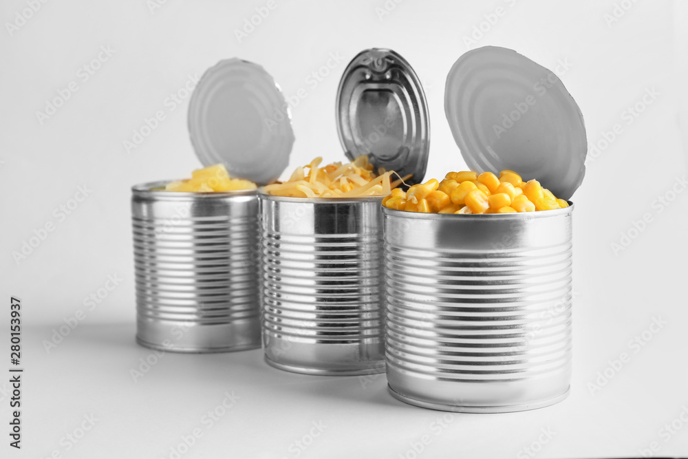 Tin cans with different food on light background