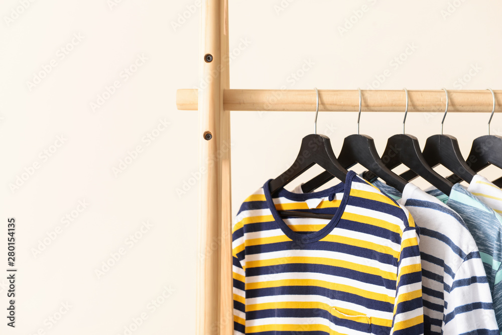 Rack with hanging clothes on color background