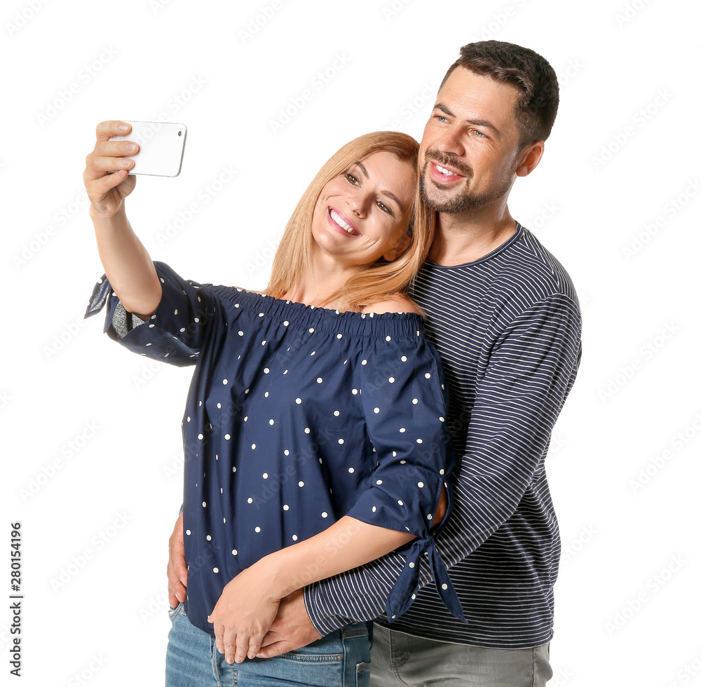 Portrait of happy couple in love taking selfie on white background