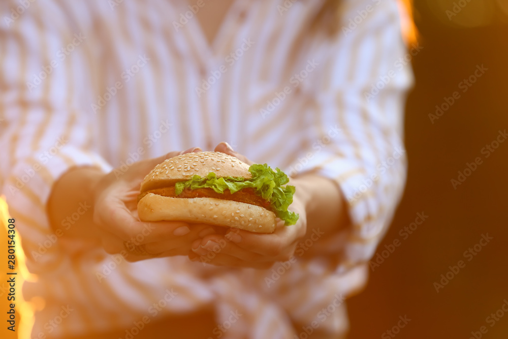 Beautiful young woman with tasty burger, closeup