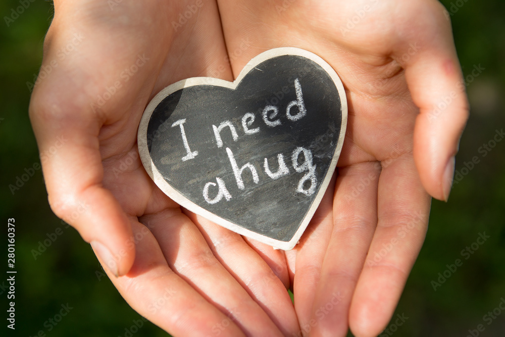 Little heart with I Need a Hug phrase in a hands. Sharing a Hug concept