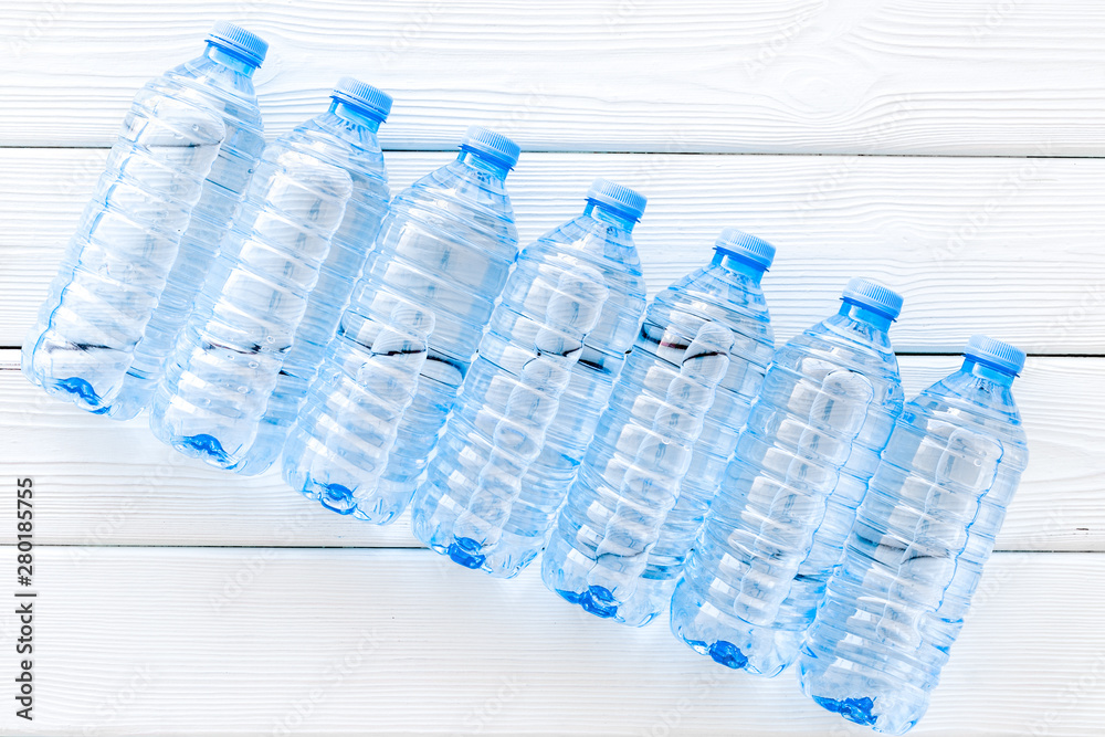 Plastic bottles with pure water on white wooden background top view