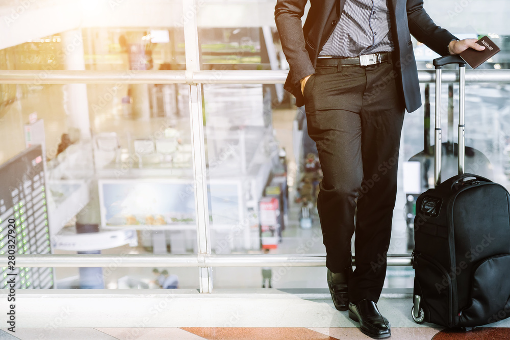 Elegant asian businessman checking email on mobile phone while walking with suitcase inside airport,