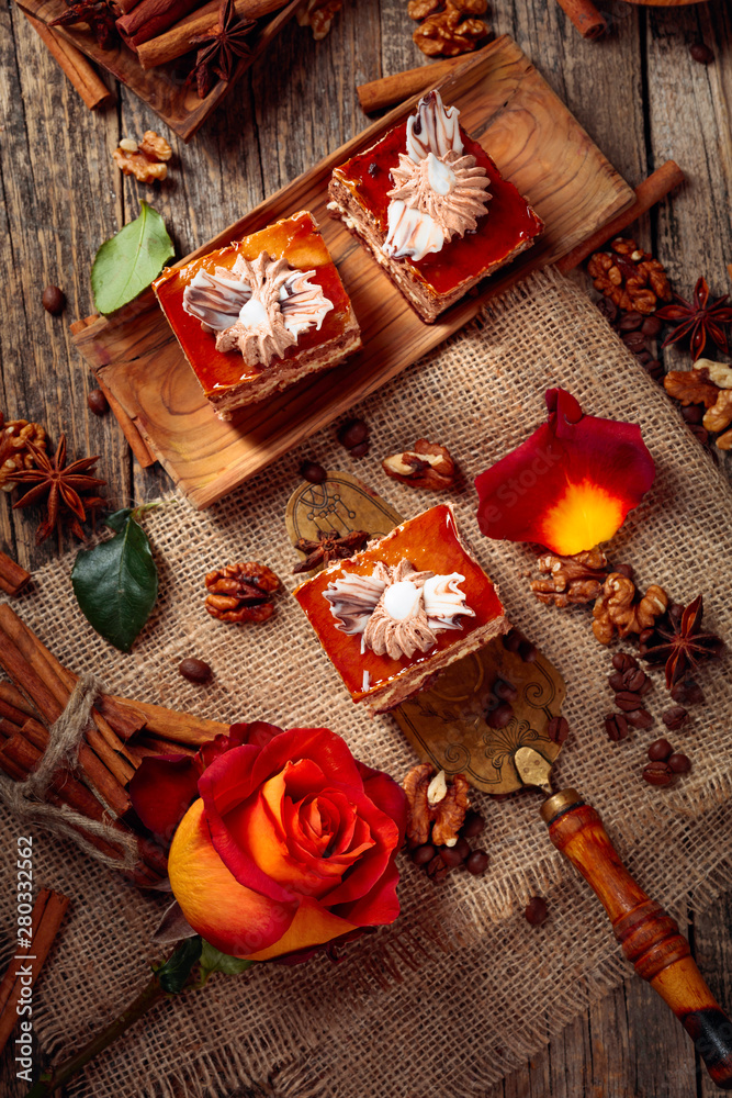 Layered cakes with cinnamon, anise, coffee beans and nuts on a old wooden table.