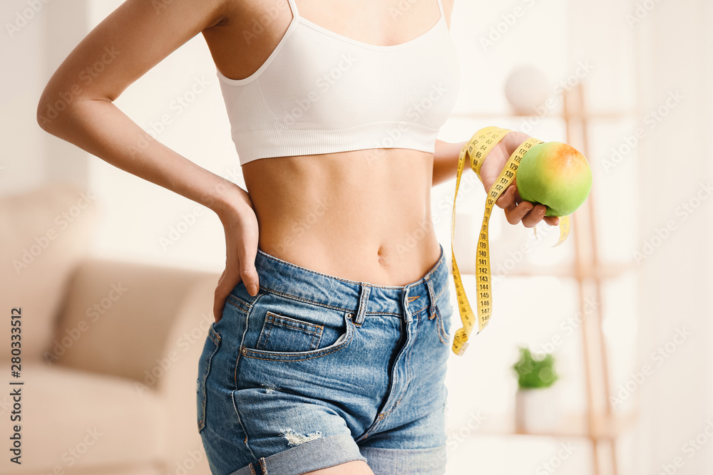 Woman with measuring tape and apple at home. Weight loss concept