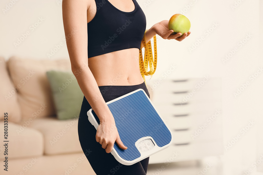 Woman with measuring tape, scales and apple at home. Weight loss concept