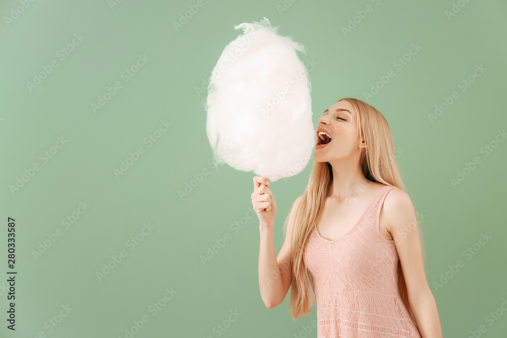 Beautiful woman with cotton candy on color background