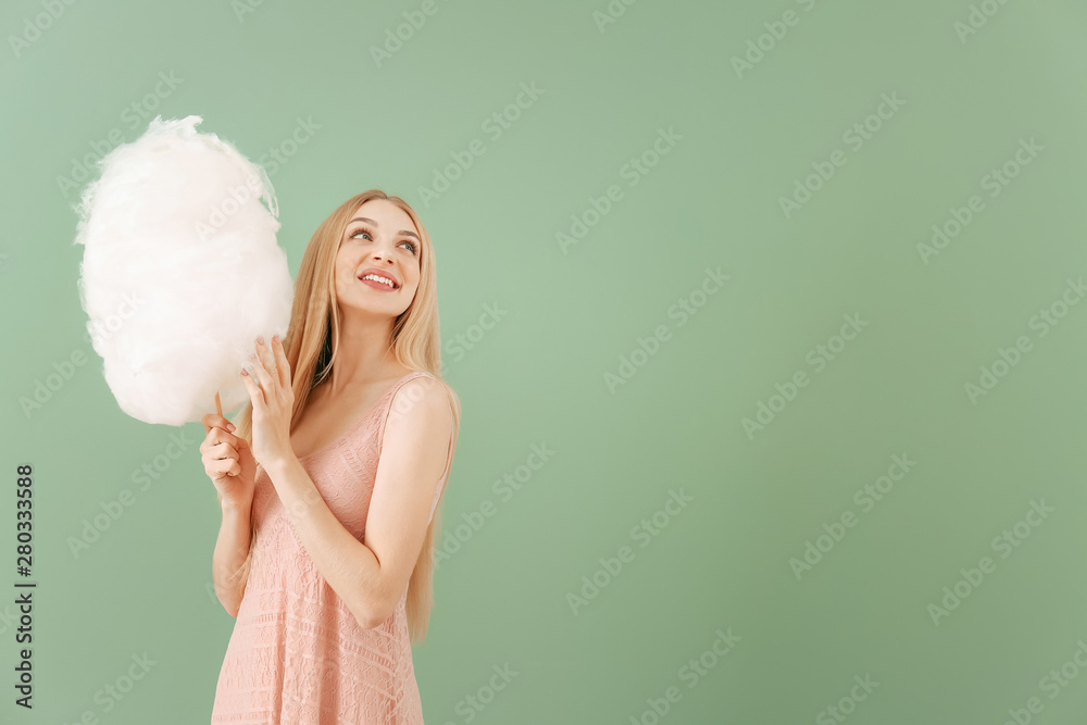 Beautiful woman with cotton candy on color background