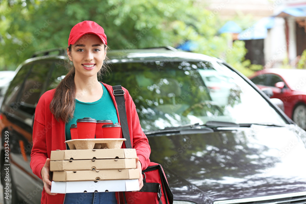 Female worker of food delivery service near car outdoors